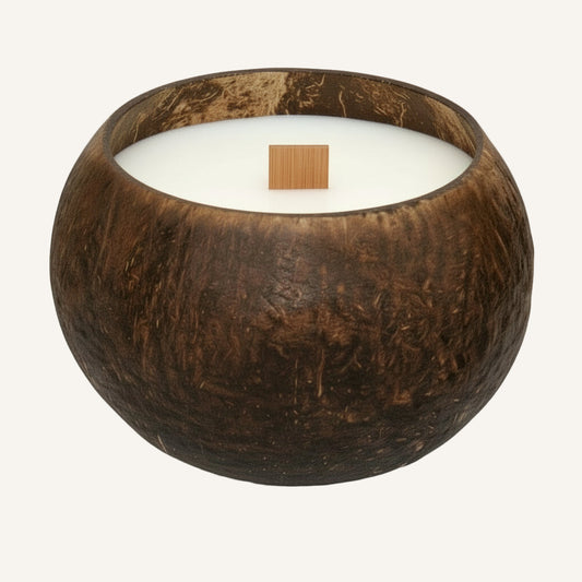 Bougie naturelle coulée dans une coque de noix de coco, mèche en bois, sur fond uni – artisanat durable Maison Moka.